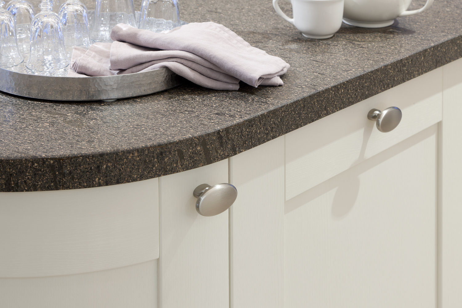 muschelweisse gebogene landhausrahmenfront mit ovalen Edelstahl-Knäufen matt gebürstet