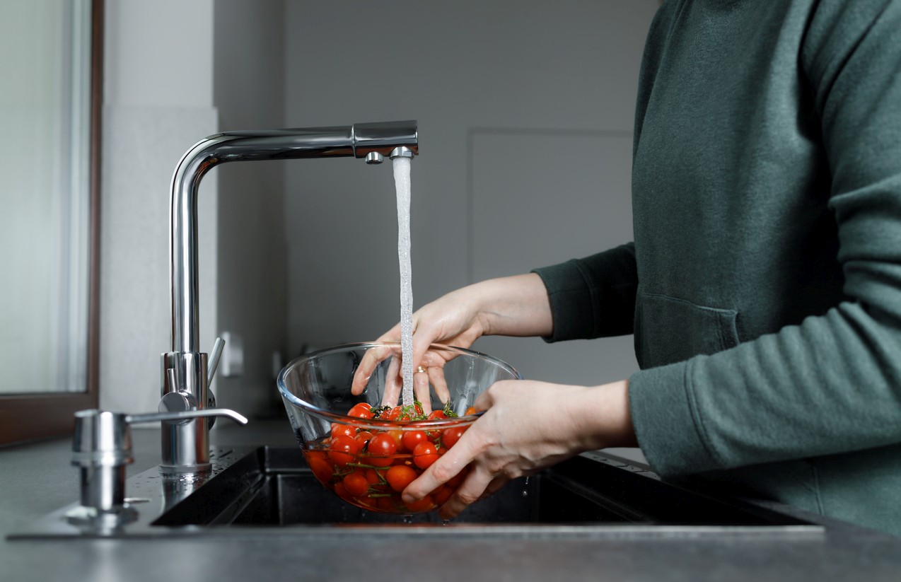 Tomaten unter fließendem Wasser waschen in der Küchenspüle