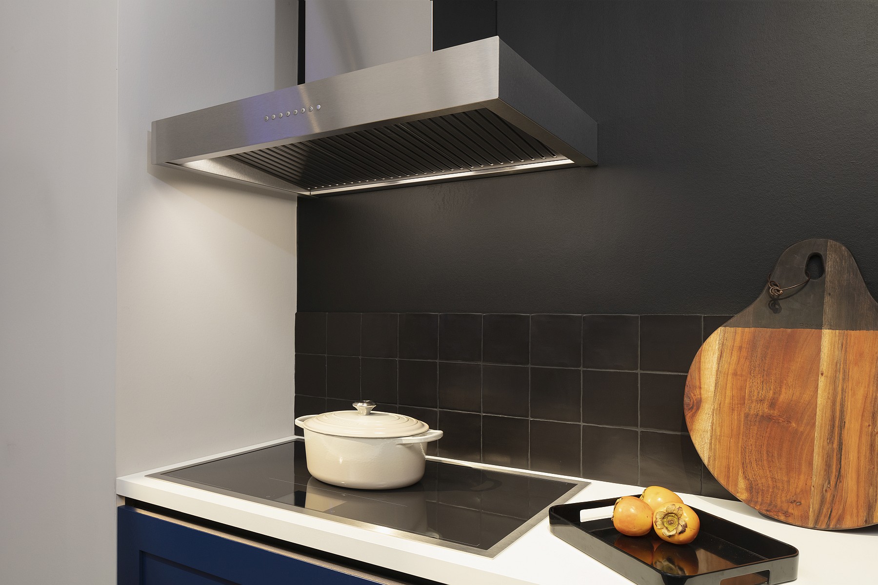 Blaue Häcker Küche mit halbhoch verlegtem schwarzem Fliesenspiegel