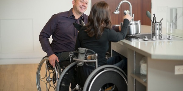 Zwei Rollstuhlfahrer haben Spaß beim Abspülen an der Küchenspüle